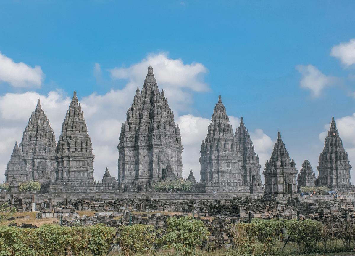 Prambanan Temple's three towering Trimurti shrines silhouetted at sunset above the Javanese plain — 9th-century Hindu temple complex, UNESCO World Heritage Site (1991, inscription 642), Yogyakarta, Indonesia.
